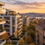 Új és régebbi budapesti lakóépületek naplementében, a háttérben a Dunával és a Parlamenttel – AI illusztráció
